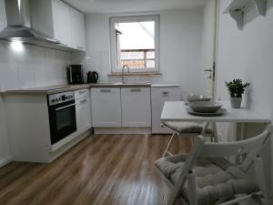 a kitchen with white cabinets and a table with a chair at Nordunterkunft in Neumünster