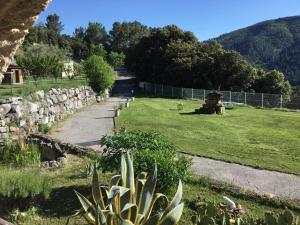 a garden with a stone wall and a grass field at Mas Auziere in Le Martinet