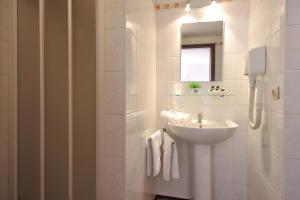 un bagno bianco con lavandino e specchio di Hôtel du Perron a Theux