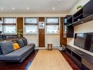 een woonkamer met een bank en een flatscreen-tv bij Pass the Keys Beautiful Museum Street Apartment in Londen