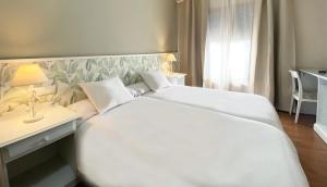 a bedroom with a large white bed and a desk at Hotel Plaza Mayor in Ocaña