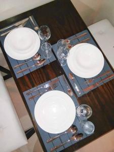 a wooden table with white plates and glasses on it at Persimmon Studios - Studio Unit- 16th Floor - 1641 in Cebu City