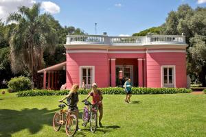 3 Personen mit Fahrrädern vor einem rosa Haus in der Unterkunft Florida Estación in Florida