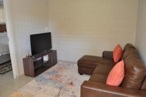 a living room with a couch and a flat screen tv at Kosi Khaya in Manguzi