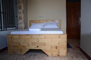 1 dormitorio con cama de madera en una habitación en Lunguya Annex Lodge, en Dar es Salaam
