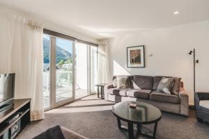 a living room with a couch and a large window at Blue Peaks Apartments in Queenstown