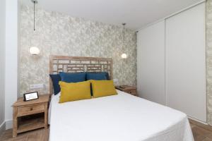 una camera da letto con un letto con cuscini blu e gialli di HomeForGuest Atico Cecilia con vistas al mar en Los Cristianos a Los Cristianos