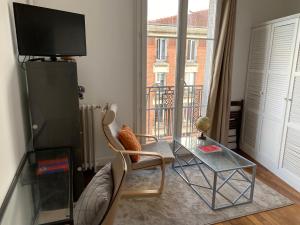 uma sala de estar com uma mesa de vidro e uma televisão em Grande chambre privative à 20 minutes de Paris em Colombes