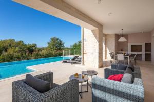 ein Wohnzimmer im Freien mit einem Pool und Gartenmöbeln in der Unterkunft Villa Celeste by ILC (Istria Luxury Collection) in Brtonigla
