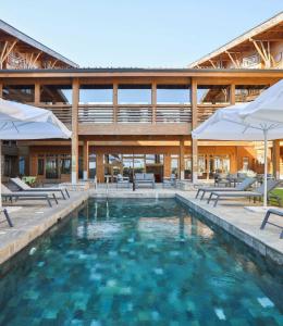 a pool with chairs and umbrellas in front of a building at Pirin Golf Hotel Private Studios in Razlog