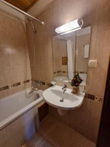 een badkamer met een wastafel, een spiegel en een bad bij Pirin Golf Hotel Private Studios in Razlog