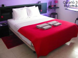 a bed with two pairs of towels on a red blanket at Alojamento Tiago & Jorge Guesthouse in Nazaré +25 photos