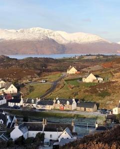 a small village with snow covered mountains in the background at Duirinish Pods with Private Hot Tubs and Duirinish Bothy with No Hot Tub in Plockton