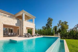 a swimming pool with chairs and a house at Villa Divine by ILC (Istria Luxury Collection) in Brtonigla