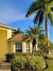 a yellow house with palm trees in front of it at Villa Tortuga - Place to Relax in Cape Coral