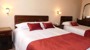 Habitación de hotel con 2 camas con almohadas rojas en Hotel Gran Libertador, en Potosí