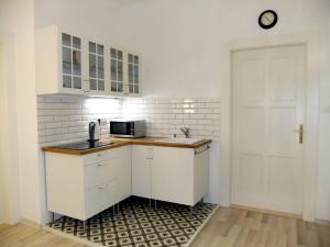 Una cocina con gabinetes blancos y una puerta blanca. en PANORAMA apartmán ajaj, en Banská Štiavnica