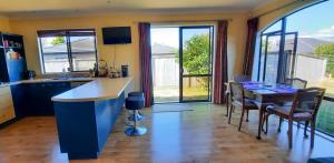 a kitchen with a counter and a table with chairs at Quiet homestay, private room with own bathroom in Paraparaumu Beach