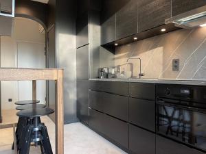 a kitchen with black cabinets and a sink and stool at Casa Clementina - 3 Bedroom Apartment in a Art-Nouveau House in Ghent +42 photos