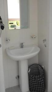 W białej łazience znajduje się umywalka i lustro. w obiekcie Carlos Gardel Tango Studio w BuenosAires