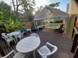 a deck with a table and chairs and a swimming pool at Complejo Refugios Marinos in Valeria del Mar