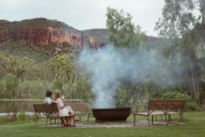 two women sitting on benches next to a large grill at Mt Mulligan Lodge in Mount Mulligan