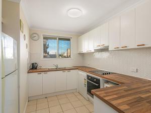 uma cozinha com armários brancos, um lavatório e uma janela em Como Unit 6 em Gold Coast