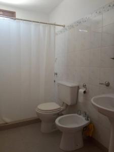 a white bathroom with a toilet and a sink at Rada in Embalse