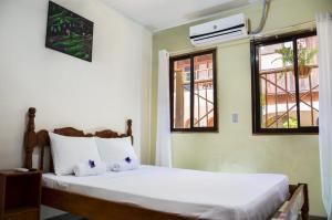 a bedroom with a bed with white sheets and windows at Cabinas Coco Alegre in Coco