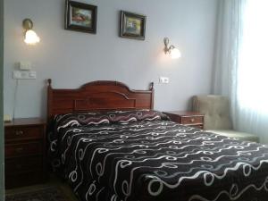 a bedroom with a bed with a black and white blanket at Hotel Los Nogales in Noja