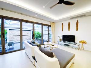 een woonkamer met een bank en een tv bij Beautiful 1br Pool Villa Walk To Bangtao Beach in Ban Thalat Choeng Thale