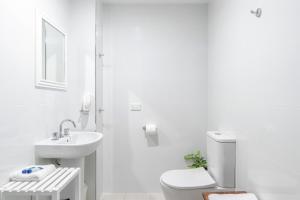 a white bathroom with a toilet and a sink at Debbie's Place in Rainbow Beach