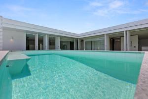 a swimming pool in front of a house at The Luxury White House in Peregian Springs
