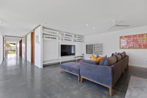 a living room with a couch and a tv at The Luxury White House in Peregian Springs