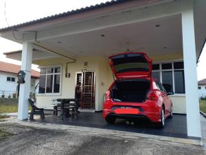 a car parked in front of a house with its trunk open at Mutiara Desaru Cottage in Bandar Penawar