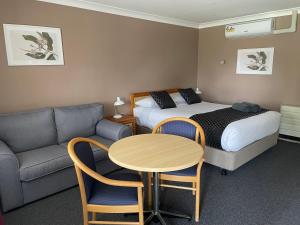 Habitación de hotel con cama, mesa y sofá en Highlands Motor Inn, en Oberon