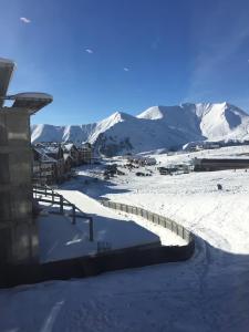 a snow covered village with mountains in the background at Amber DeLUX Atrium-Neo, New Gudauri in Gudauri
