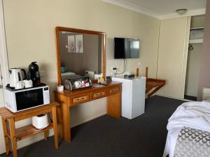 a hotel room with a vanity with a mirror and a refrigerator at Highlands Motor Inn in Oberon