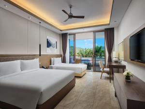 a hotel room with a bed and a television at Narada Resort Hotel Sanya Pleasant Bay in Sanya
