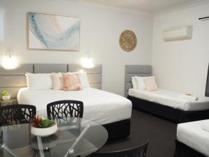 a hotel room with two beds and a glass table at The Esplanade Motel in Warners Bay +88 photos