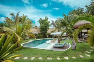 a beach with a pool, lawn chairs, and trees at Mule Malu Tropical Stay in Uluwatu