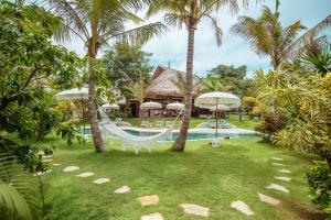 a beach with a pool, chairs, and lawn chairs at Mule Malu Tropical Stay in Uluwatu