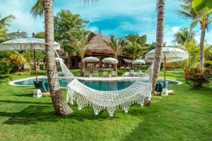 a hammock in front of a resort with a pool at Mule Malu Tropical Stay in Uluwatu