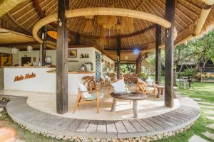 an outdoor patio with chairs and tables and a large umbrella at Mule Malu Tropical Stay in Uluwatu