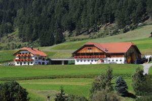two large white buildings in a green field at Klaudehof in Dobbiaco