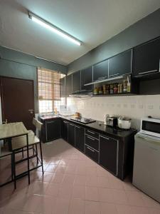 a kitchen with black cabinets and a table in it at LEPAK-LEPAK HOMESTAY @ INDERA MAHKOTA in Kuantan