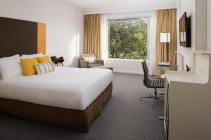 a hotel room with a large bed and a desk at Rydges Bankstown in Bankstown