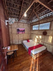 ein Schlafzimmer mit einem Bett und einem Tisch in einem Zimmer in der Unterkunft RedDoorz Hostel Monaliza Surf Resort in San Juan