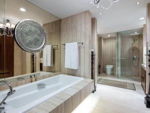 a bathroom with a large tub and a large mirror at ARTOTEL Suites Bianti Yogyakarta, CHSE Certified in Yogyakarta