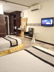 a hotel room with two beds and a flat screen tv at Shervinton Executive Boutique Hotel in Tawau